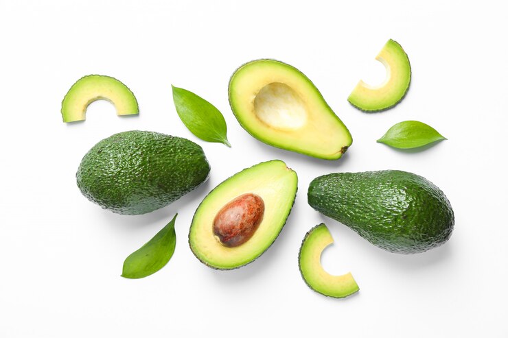 Foto composición plana laica con aguacates maduros y hojas en blanco