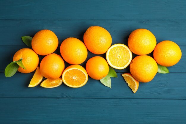 Composición plana laico con naranjas maduras y hojas sobre fondo de madera.