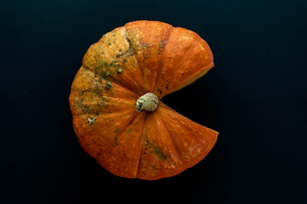 Composición plana laicos calabaza naranja en forma de pacmen sobre un fondo negro