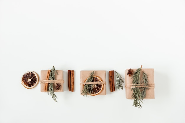 Composición plana de Navidad de cajas de regalo artesanales. Caja de papel marrón hecha a mano con rama de árbol de Navidad y ramas de canela y naranja seca. Copia espacio