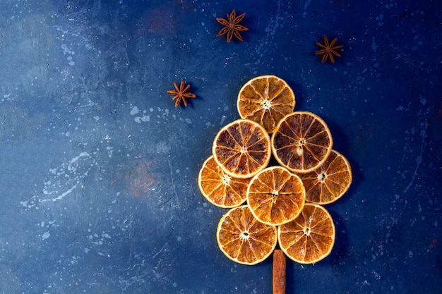 Composición plana de Navidad. Árbol de naranjas secas, canela y anís sobre fondo oscuro. Navidad, vacaciones de invierno, año nuevo concepto. Bodegón romántico.