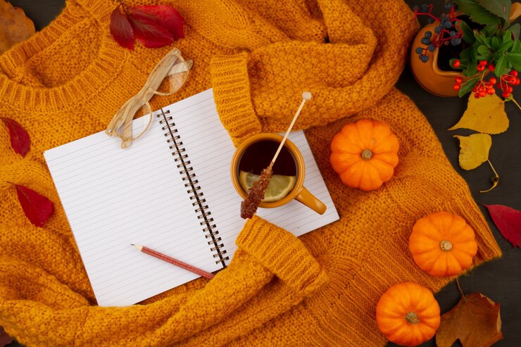 Composición plana de otoño con hojas de otoño, una taza de té caliente y un cálido suéter naranja de lana