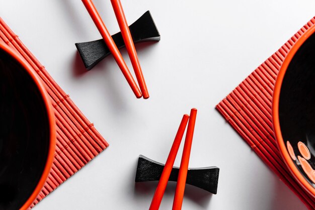 Composición plana con palillos rojos, servilletas y tazas.