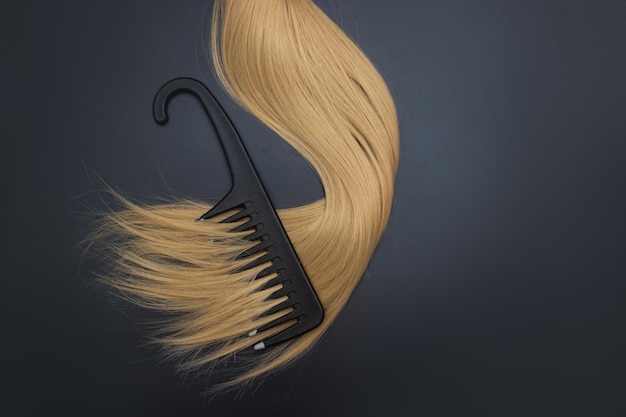 Composición plana con peine de cabello claro y espacio para texto en fondo negro Servicio de peluquería Cuidado personal y bienestar Concepto de salón de peluquería Herramientas de peluquería profesional