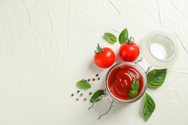 Composición plana con tomates frescos, albahaca, pimienta y salsa en un frasco de vidrio para texto