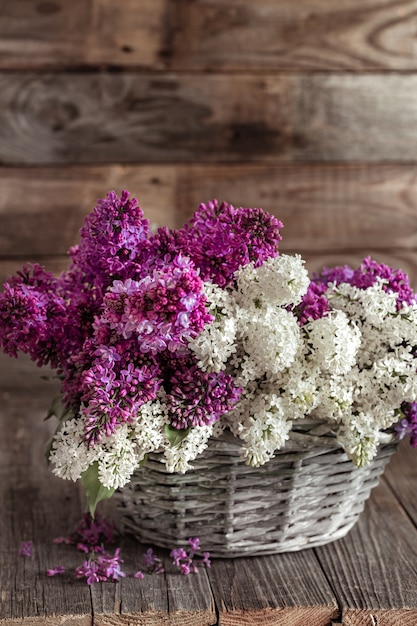 Composición de primavera con flores lilas en una canasta de mimbre. Cestas de regalo y concepto de entregas de flores.