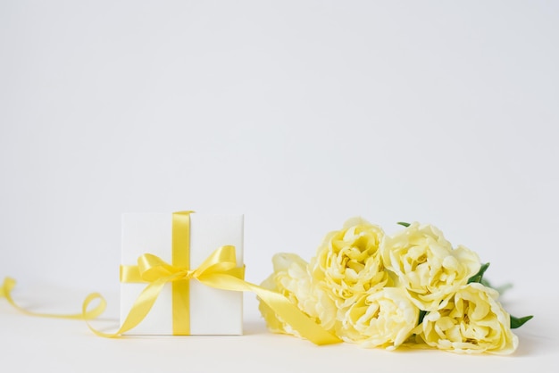 Composición primaveral de un ramo de tulipanes amarillos un regalo con un lazo amarillo y cinta