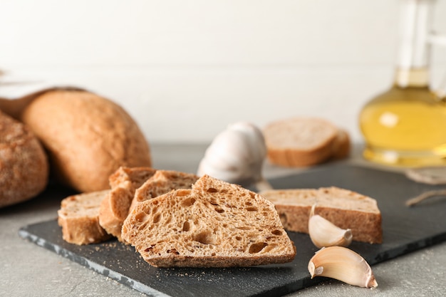 Composición con productos de panadería, ajo y aceite de oliva en espacio gris, primer plano y espacio para texto