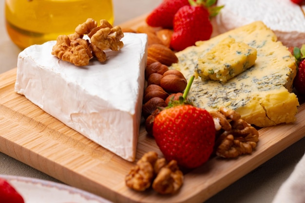 Composición de queso y frutas sobre mesa gris.