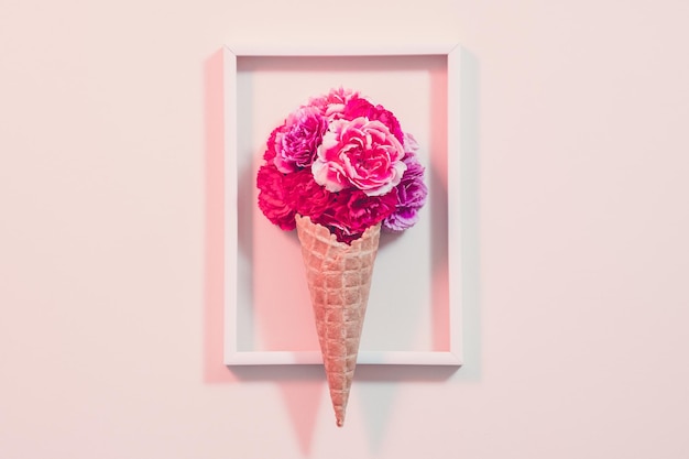 Composición de regalo conceptual Clavel rosa en cono de helado dispuesto en marco Fondo rosa