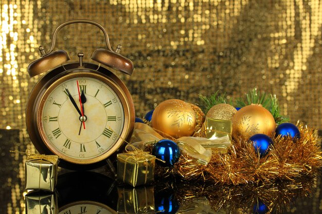 Composición de reloj y adornos navideños sobre fondo brillante