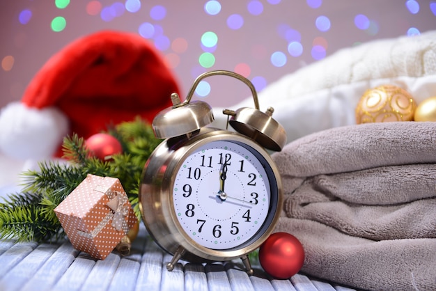 Composición con reloj despertador retro y decoración navideña sobre fondo brillante