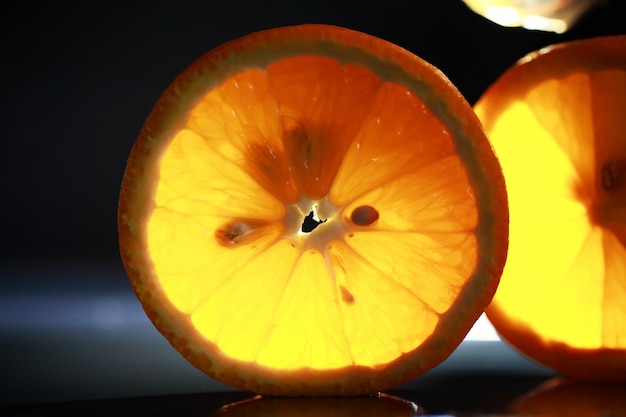 Composición con rodajas de naranja y pomelo sobre un fondo negro. Una rodaja de naranja con luz de fondo sobre un fondo negro con gotas de agua. Jugosa naranja sobre una mesa.