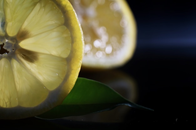 Composición con rodajas de naranja y pomelo sobre un fondo negro. Una rodaja de naranja con luz de fondo sobre un fondo negro con gotas de agua. Jugosa naranja sobre una mesa.