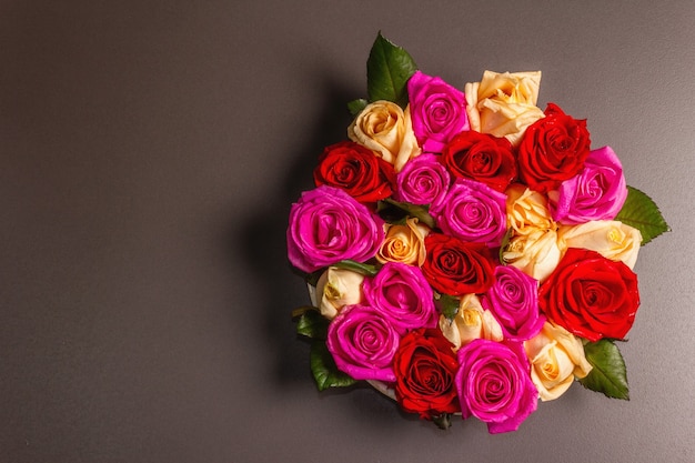 Composición de rosas frescas multicolores sobre soporte de cerámica. El concepto festivo para bodas, cumpleaños, 8 de marzo, día de la madre o San Valentín. Tarjeta de felicitación, endecha plana, fondo de piedra negra