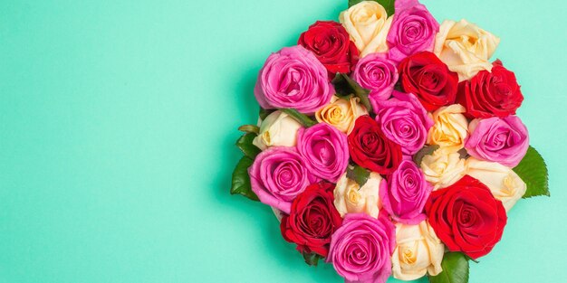 Composición de rosas frescas multicolores sobre soporte de cerámica. El concepto festivo para bodas, cumpleaños, 8 de marzo, día de la madre o San Valentín. Tarjeta de felicitación, endecha plana, fondo turquesa mate