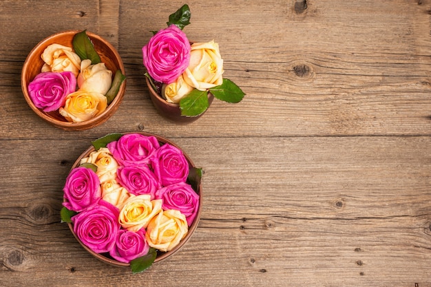 Composición de rosas multicolores frescas en utensilio de cocina. El concepto festivo para bodas, cumpleaños, 8 de marzo, día de la madre o San Valentín. Tarjeta de felicitación, endecha plana, mesa de madera vintage