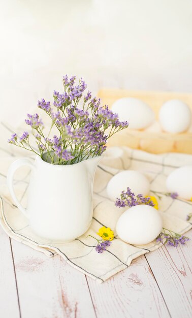 Composición rústica Cesta con huevos blancos y flores frescas sobre fondo de madera