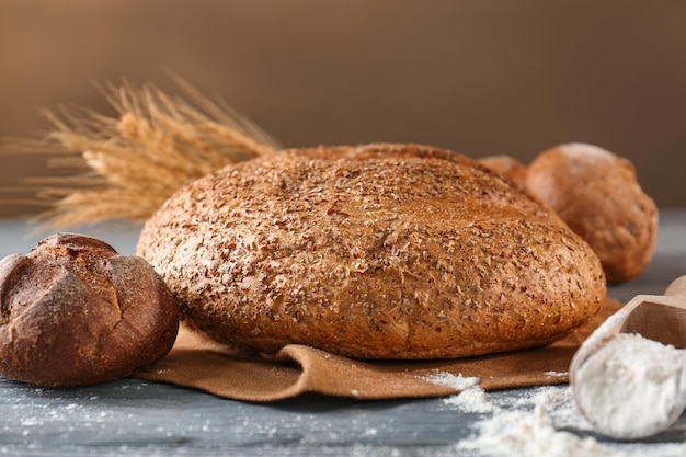 Composición con sabroso pan y harina de trigo sobre mesa de madera