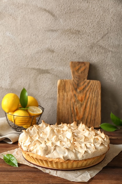 Composición con sabroso pastel de merengue de limón sobre mesa de madera