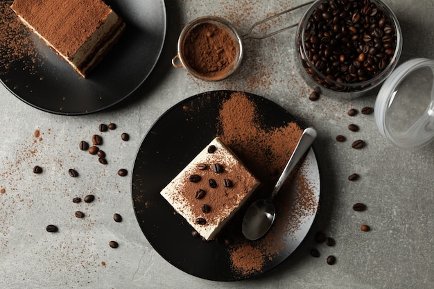 Composición con sabroso tiramisú y granos de café sobre fondo gris