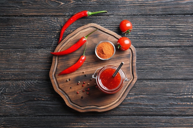 Composición con salsa de chili sobre mesa de madera