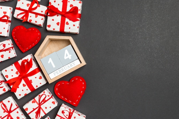Composición de San Valentín de cajas de regalo, calendario de madera y corazones textiles rojos