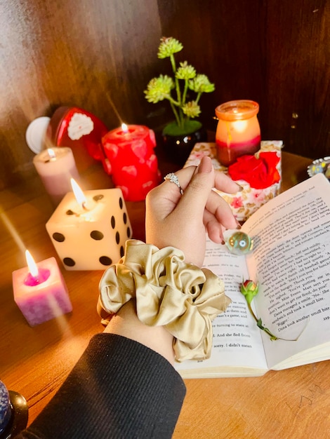 composición de scrunchie de seda de morera con velas de libro flores en la mano modelo de amplificador