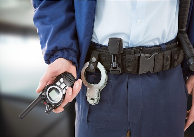 Foto composición de la sección media del guardia de seguridad masculino sosteniendo un walkie talkie sobre fondo borroso