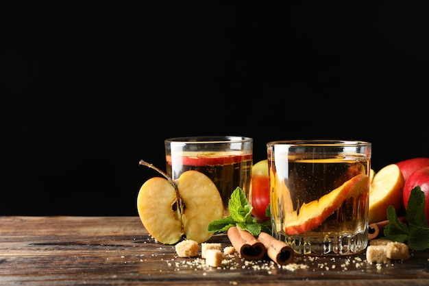 Composición con sidra, azúcar, canela y manzanas en la mesa de madera