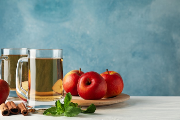 Composición con sidra, canela y manzanas en madera blanca