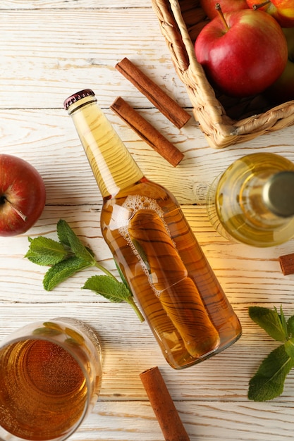 Foto composición con sidra, canela y manzanas en madera blanca