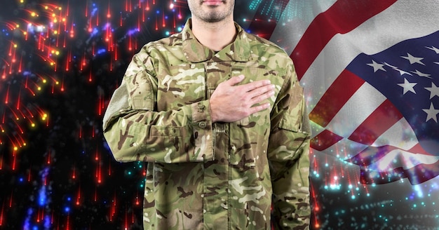 Composición del soldado masculino con la mano en el corazón, sobre la bandera americana y fuegos artificiales