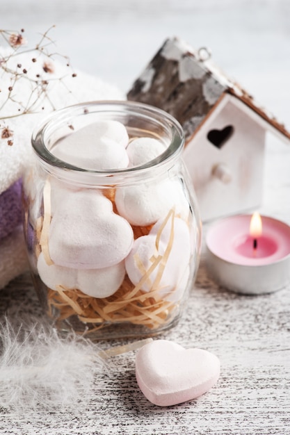 Composición de spa con corazones de bomba de baño y flores secas en pared rústica en estilo monocromo. Velas y sal. Tratamiento de belleza y relax