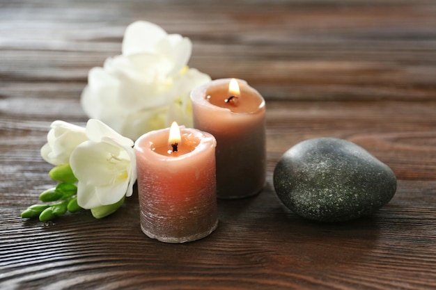 Composición de spa con guijarros de velas y aceite aromático sobre fondo de madera