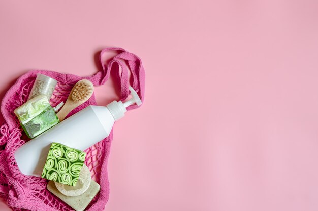 Composición de spa plana con artículos de higiene personal y accesorios de baño en una bolsa de hilo.