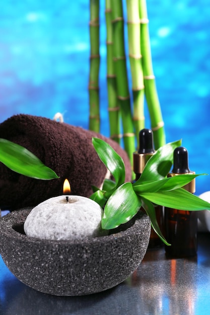 Composición de spa con velas y bambú en la mesa sobre fondo azul.