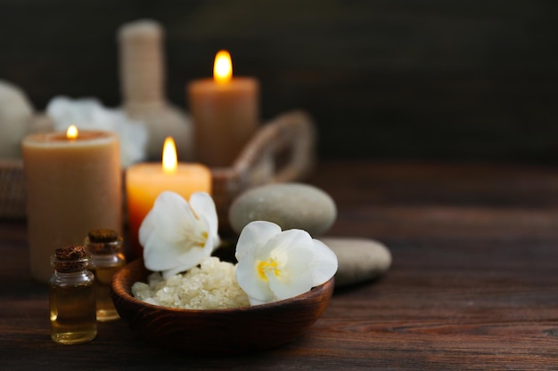 Composición de spa con velas encendidas sobre fondo de madera en la oscuridad