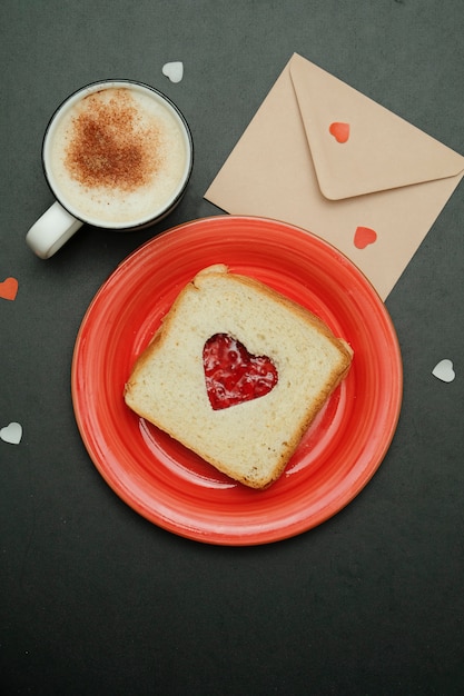 Composición para la tarjeta del día de San Valentín con café, sobre y sandwich en forma de corazón