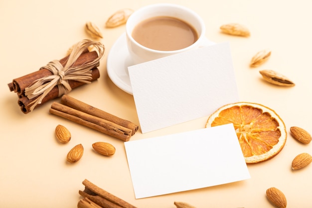 composición de tarjetas de presentación de papel blanco, almendras, canela y taza de café.