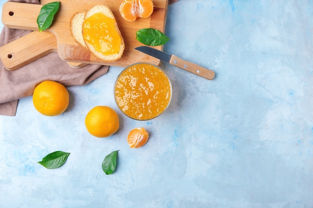 Composición con tarro de mermelada dulce y mandarinas en mesa