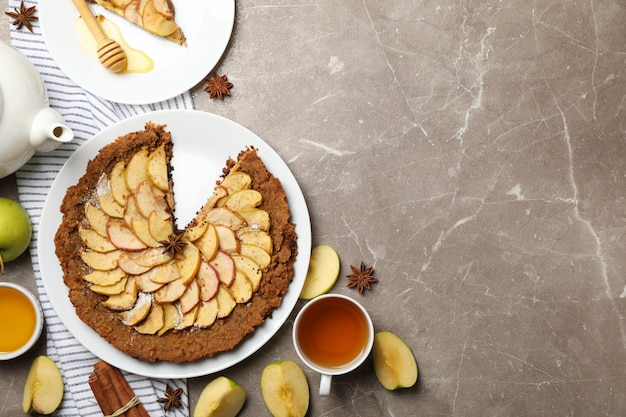 Composición con tarta de manzana e ingredientes sobre fondo gris, vista superior