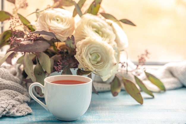 Composición con una taza de flores de té y un elemento de punto