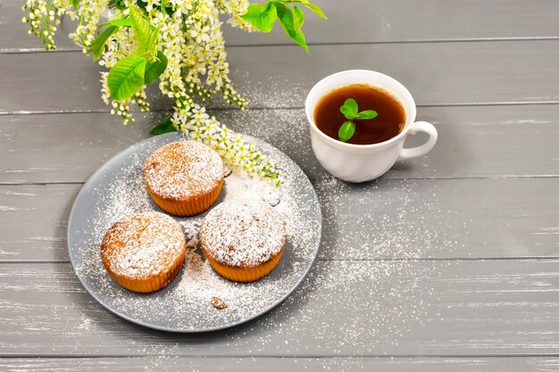 Composición con una taza de pastelitos de té y flores blancas sobre un fondo de madera