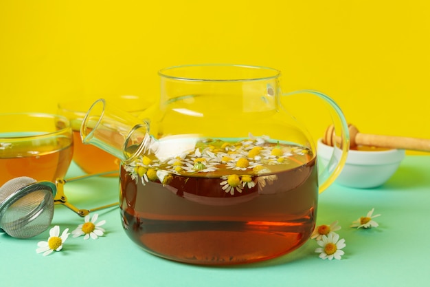 Composición con té de manzanilla en la mesa de menta contra amarillo