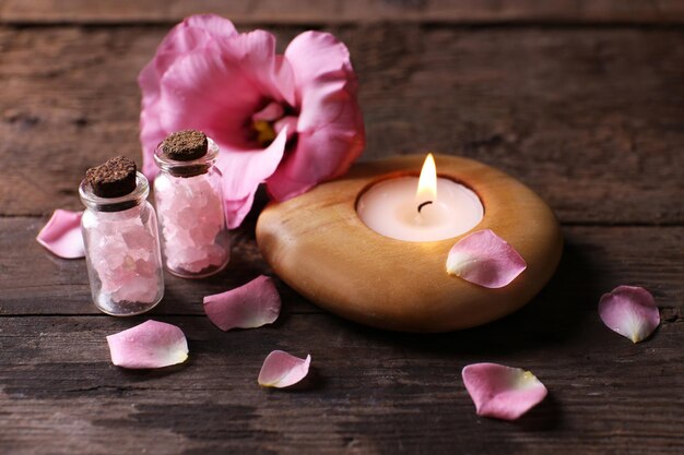 Composición de ternura de una vela encendida con pétalos de flores sobre un fondo de madera