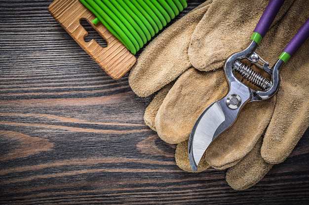 Composición de tijeras de podar guantes de seguridad de cuero amarre de alambre suave en concepto de jardinería de tablero de madera.