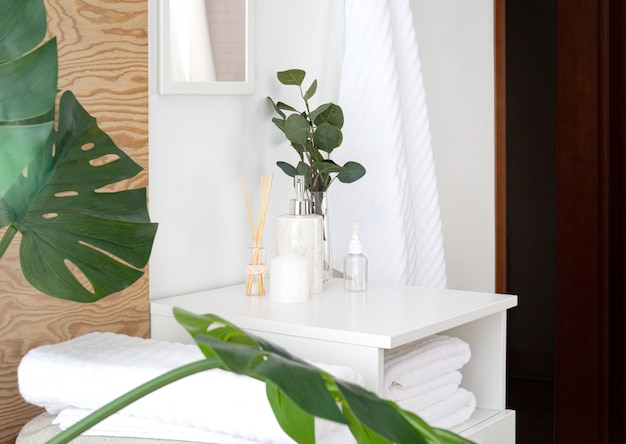 Foto composición de toallas y accesorios de baño en el interior. baño fresco y agradable con elementos de madera, flores, hojas de monstera tropical y espejo.