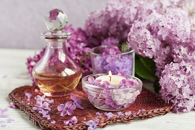 Composición del tratamiento de spa con sal marina natural, aceite aromático y flores de color lila en madera blanca
