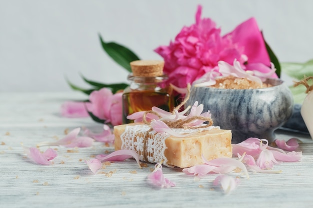 Composición del tratamiento de spa con sal marina natural, aceite aromático y flores de peonías en madera blanca